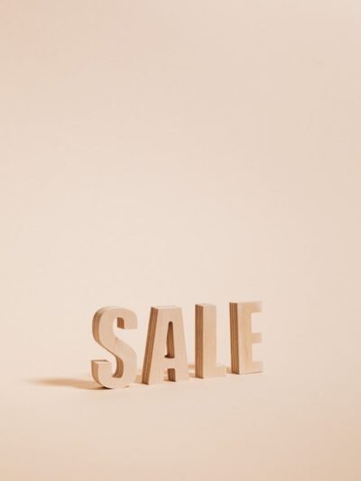 Wooden letters spelling SALE on a neutral beige background, perfect for promotions.